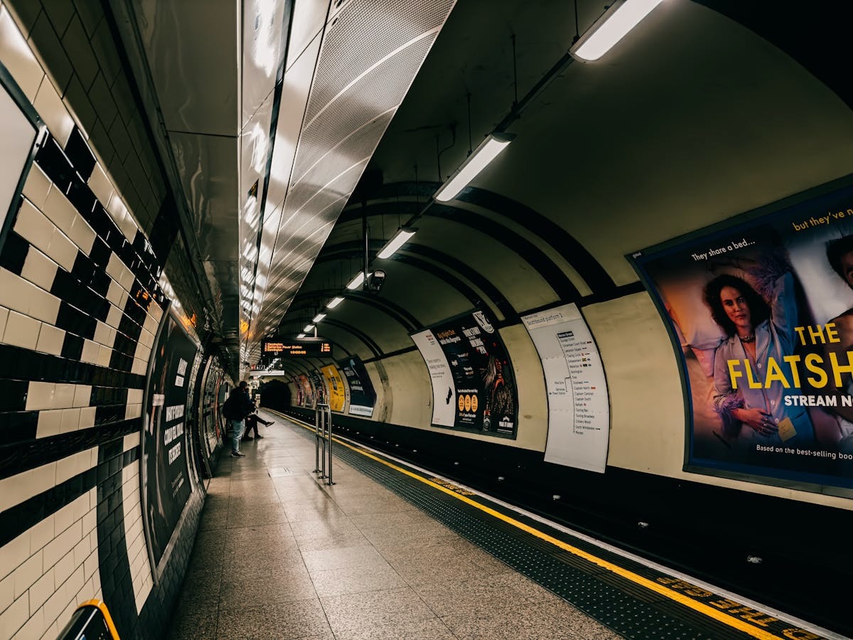 Empty subway station platform with fluorescent lighting and tiled walls