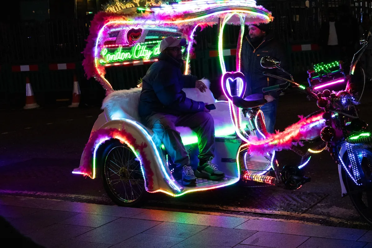 A pedicab decorated with colourful neon lights at night