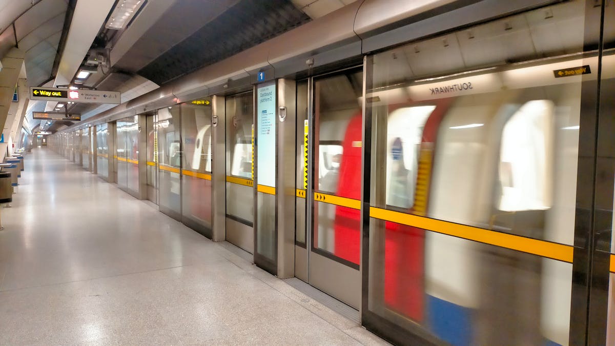 Platform edge doors at Southwark station on the Jubilee line, with a train passing behind the glass barriers